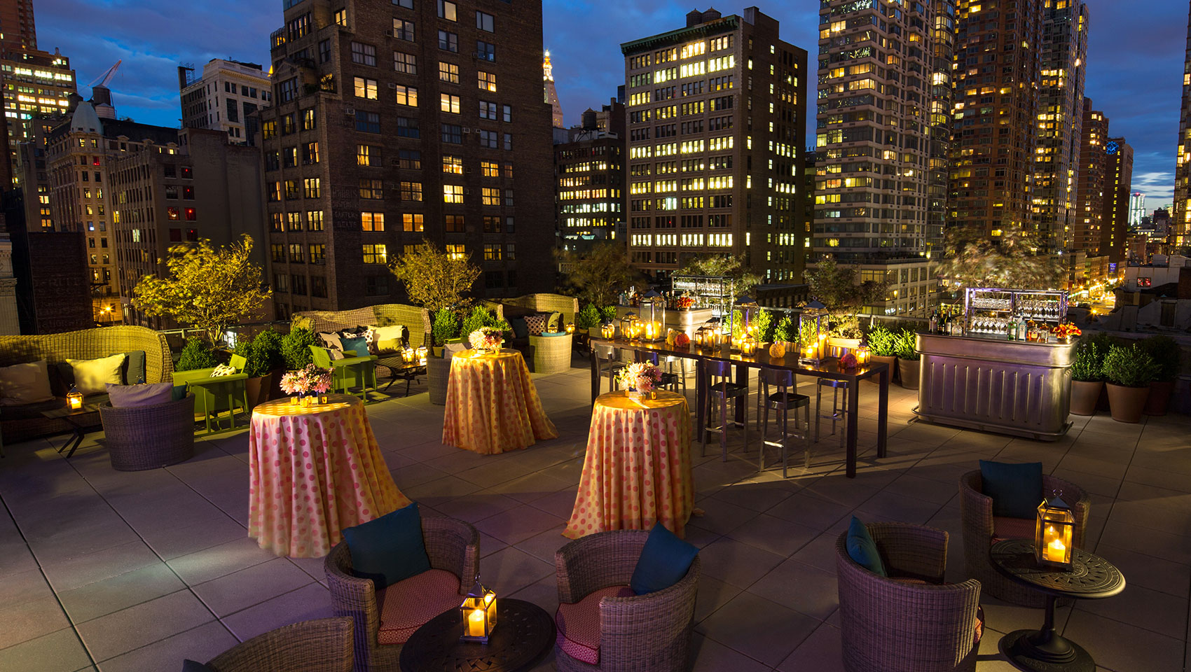 Kimpton Hotel Eventi Veranda set up for outdoor event with tables and bar against city building views at night
