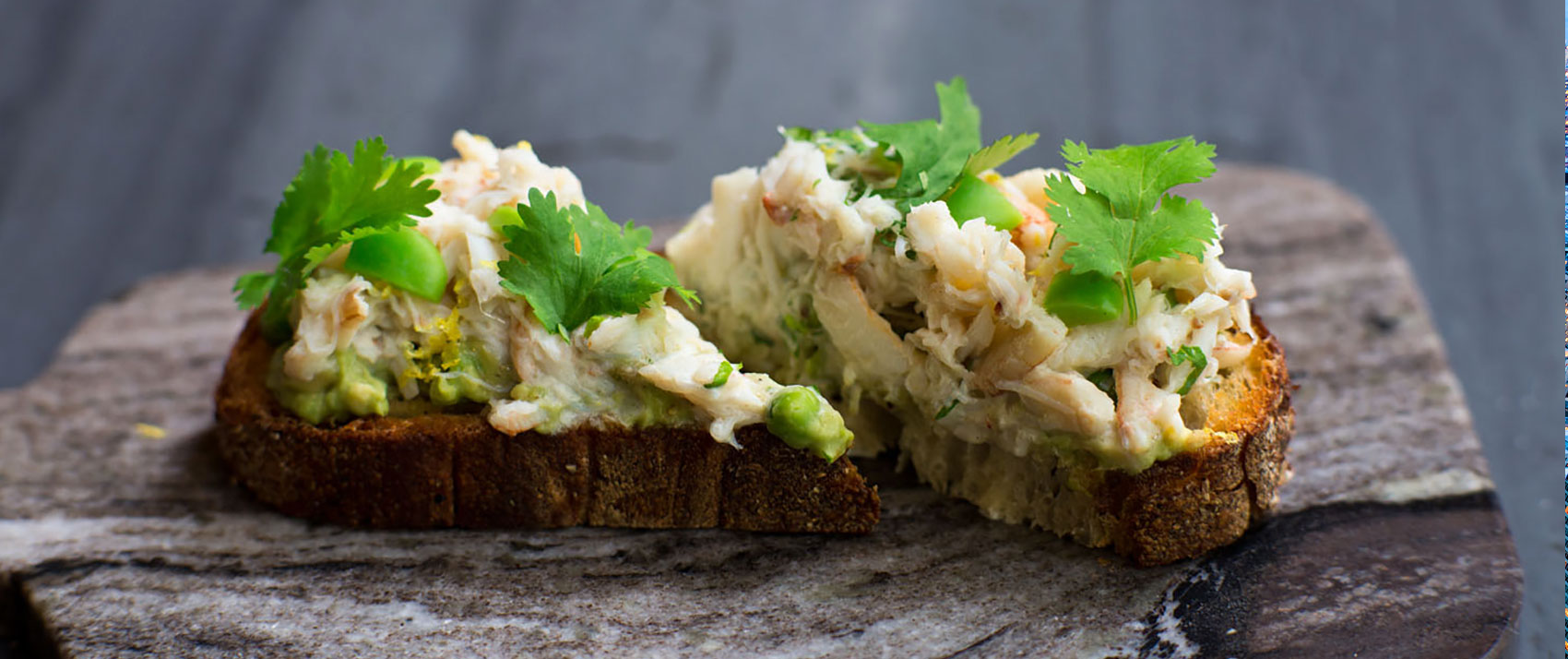 Toast with avocado, herbs, and seafood on top